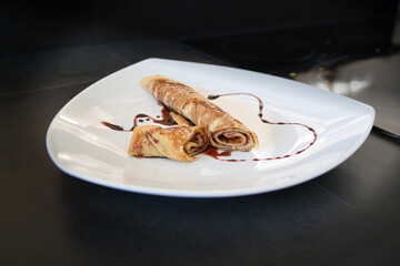 Nachtisch, Süßes Dessert Crepes Pfannkuchen, Sirup in Herzform, dekoriert auf weißem Teller