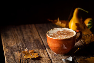 Autumn pumpkin spice coffee with cream and cinnamon on wooden background