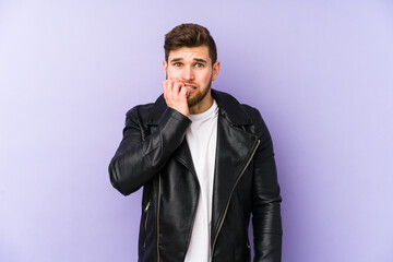 Young man isolated on purple background biting fingernails, nervous and very anxious.