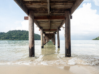 perspective of wooden bridge over the transparent sea water near beach. jetty on turquoise sea in sunny day. copy space provided. travel concept. Thailand.