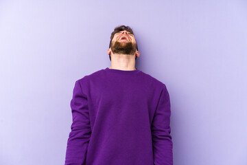 Young caucasian man isolated on purple background relaxed and happy laughing, neck stretched showing teeth.