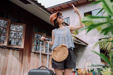 Plakat Beautiful asian woman traveler in summer casual clothes and hat with trolley luggage in local hotel.
