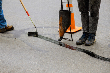 Fototapeta na wymiar Sealing joint crack in asphalt road surface restoration work.