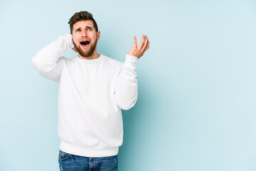 Young caucasian man isolated on blue background screaming with rage.