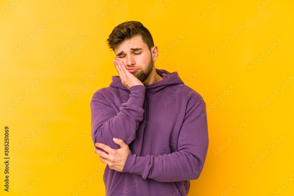 Wall mural Young caucasian man isolated on yellow background who is bored, fatigued and need a relax day.