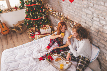 Couple eating breakfast in bed on Christmas morning