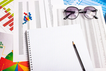 On the table are reports, a blank white sheet of paper with a pen, glasses. Workplace close-up. Copy space