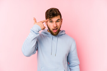 Young caucasian man isolated on pink background showing a disappointment gesture with forefinger.