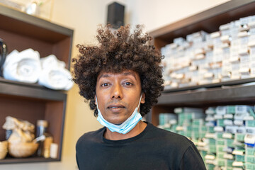 portrait of Mauritius hairdresser during the pandemic period of coronavirus, new normal concept of precautions at work with face mask, hair stylist of African descent