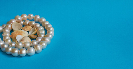 Marine layout. Pearl beads and lots of small shells on a blue background.