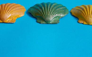 Marine layout. Three seashells painted orange, yellow, and green on a blue background.