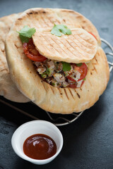 Closeup of grilled pitas with doner meat and vegetables, vertical shot on a black stone background, selective focus