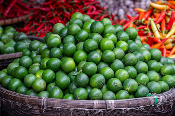 Green oranges for sale at street food market in the old town of Hanoi, Vietnam.