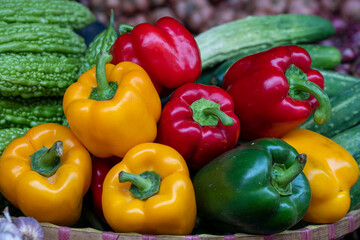 Green, yellow and red sweet peppers for sale at street food market in the old town of Hanoi, Vietnam.