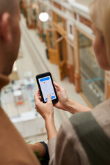 Rear view of couple using mobile phone to order the taxi they sitting at the restaurant