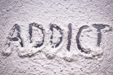 Addict text written in white flour powder. Concepts of addiction and drug abuse, people turning to narcotics in the hard times of covid global pandemic