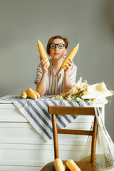 Fototapeta premium Young pretty girl on a gray background holding corn cobs in her hands