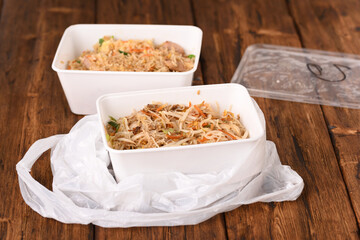 Chinese fast food in a plastic bag on the wooden table.