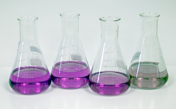 The Erlenmeyer Conical flask on bench laboratory, with green and purple solvent forming reaction between boric acid and ammonia solution analysis concentration in wastewater sample. Selective focus.