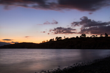Fototapeta na wymiar long exposure landscape that includes mountain silhouette, lake, clouds at the sundown