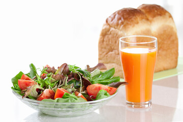 サラダと野菜ジュースとパンの朝食