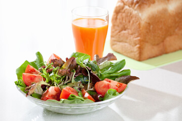 サラダと野菜ジュースとパンの朝食