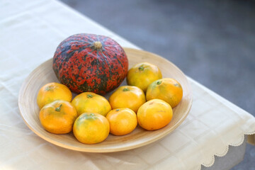 Wooden bowl with tangerines and hokkaido pumpkin. Selective focus.