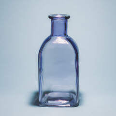 Purple empty glass bottle on light blue background