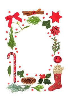Christmas festive border with red bauble decorations, stars, holly & winter greenery with loose berries on white background. Abstract Xmas composition. Flat lay, top view, copy space.