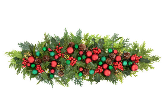 Christmas green & red bauble decoration with winter greenery of holly, ivy, mistletoe, cedar cypress & pine cones  on white background. Festive composition for the holiday season.
