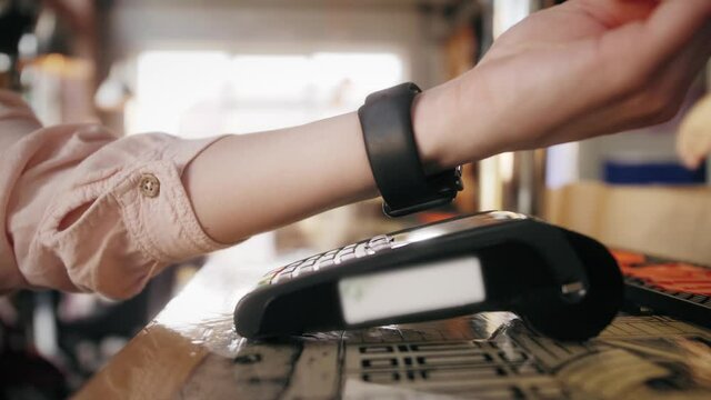 Customer paying with an NFC contactless smartwatch with a card machine. Paying in a coffee shop by a smartwatch. NFC Technology.