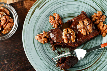 Piece of chocolate cake with nuts on green plate