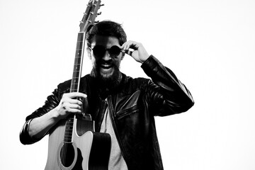 A man holds a guitar in his hands music emotions black leather jacket dark glasses studio light background