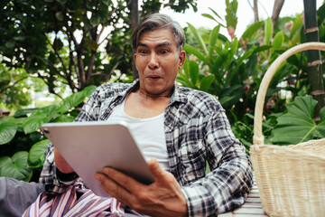 Asian elderly farmer using digital tablet to sell product from his farm.