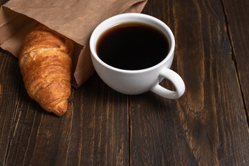 Cup of coffee and croissant in paper bag
