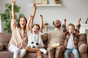 family of fans watching a football match and celebrating goal on TV at home.