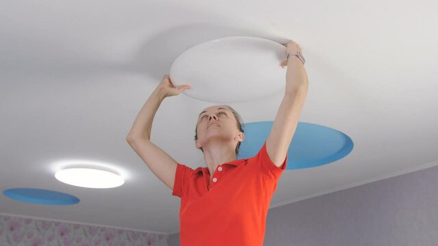 The woman in the room sets the led ceiling light.