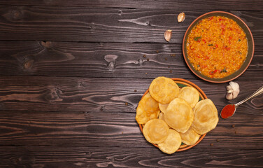 Indian cuisine. Luchi tortillas with cooked and fresh vegetables. Top View. Copyspace, wood background.