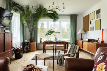Modern scandinavian home interior of living room with design retro furniture, tropical plant, window, decoration and elegant personal accessoreis in stylish home decor.