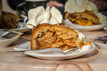 Piece of apple pie topped with whipped creamon a fake marble plastic cafe table