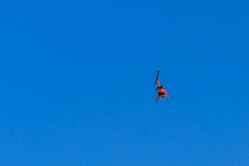 Obraz na płótnie Canvas Flying orange helicopter in blue sky