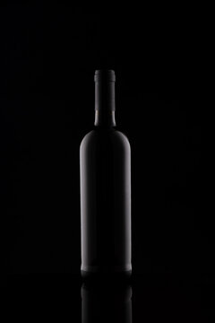 Wine bottle silhouette isolated on dark background. Mockup of bottle on dark backdrop. Studio photography.
