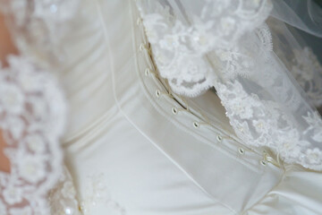 Obraz na płótnie Canvas Corset of the bride's wedding dress close-up, fabric with lace and clasp