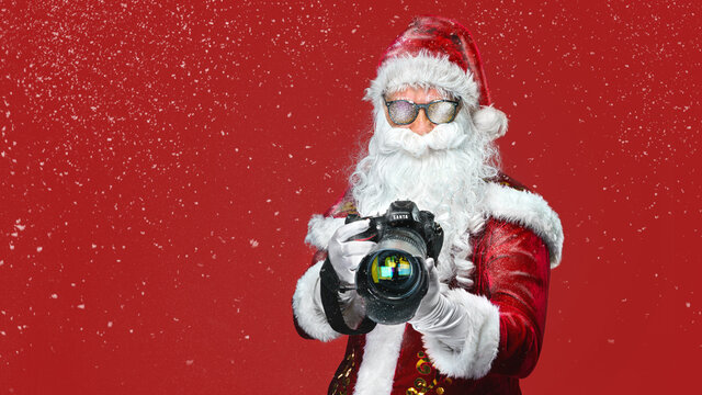 cool Santa Claus taking holiday pictures - isolated on the red background