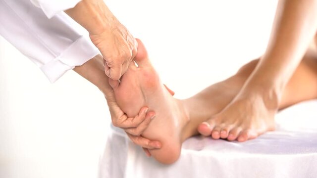 masseuse massaging the feet and pooling the toes of a young woman on a white background