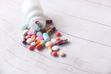 close up of colorful pills spilling on wooden background 
