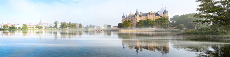 Schwerin panorama of the castle, bridge and town with reflection in the lake and morning fog, copy space