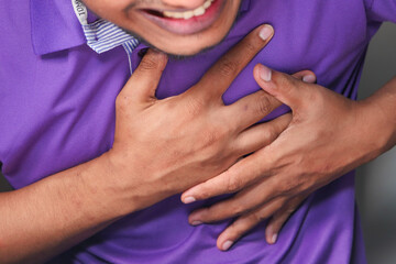young man suffering pain in heart and holding chest with hand 