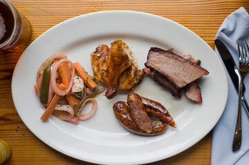 Barbecue catering platter with variety of meats. Traditional Texas BBQ: Beef brisket, beef ribs, pork ribs, sausage links, black pepper roasted chicken, and turkey served with homemade sauce.