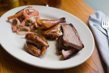 Barbecue catering platter with variety of meats. Traditional Texas BBQ: Beef brisket, beef ribs, pork ribs, sausage links, black pepper roasted chicken, and turkey served with homemade sauce.